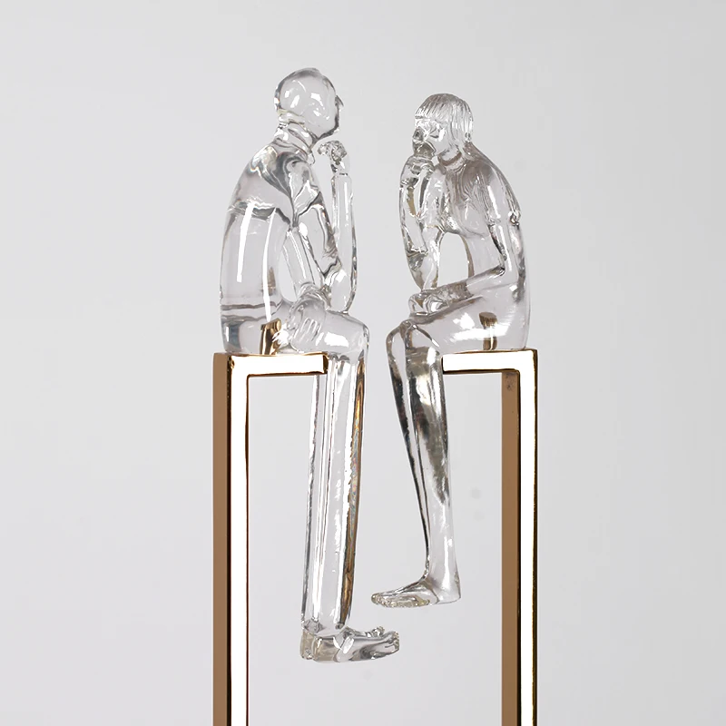 Творческая пара прозрачных абстрактных фигурок из смолы сидя на металлической