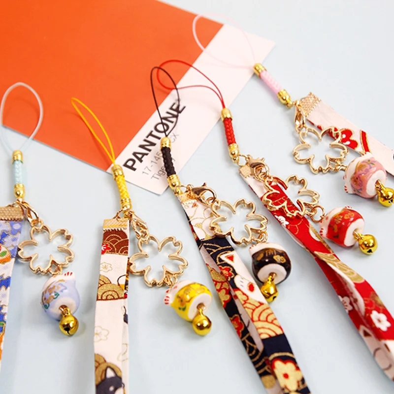 Японский брелок «Счастливый кот» цвета конфетки с колокольчиком и подвеской в виде вишневого цветка на верёвке для флешки или рюкзака. Аксессуары для ювелирных изделий.