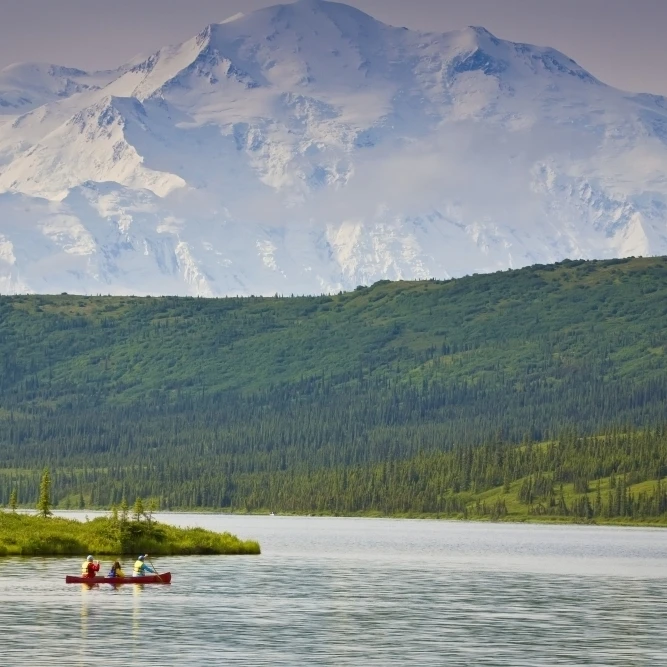 Три человека в одном каноэ на озере чудо с Mt. Mckinley заднем плане |
