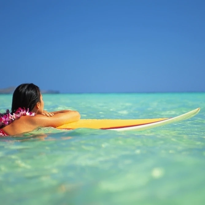 Hawaii Oahu Lanikai женщина отдыхает на доске для серфинга смотря вне ясной бирюзовой