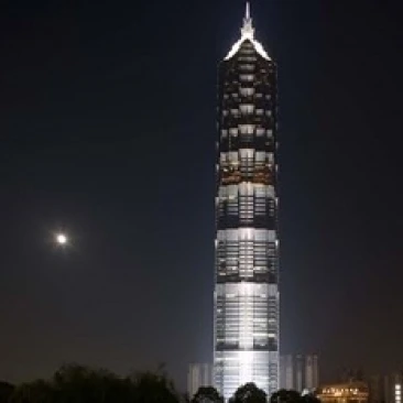 Полнолуние поднимается за башней Цзинь МАО в экономической зоне Пудун Шанхай