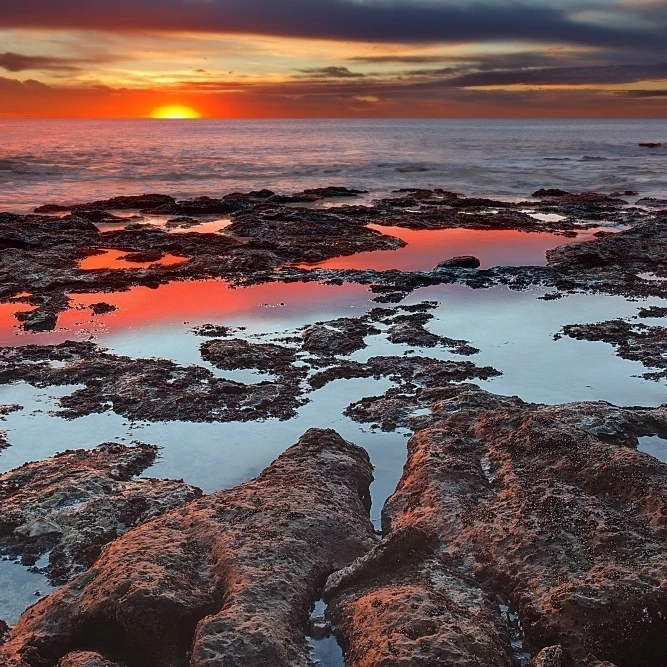 Приливные бассейны отражают цвета восхода во время осеннего равноденствия
