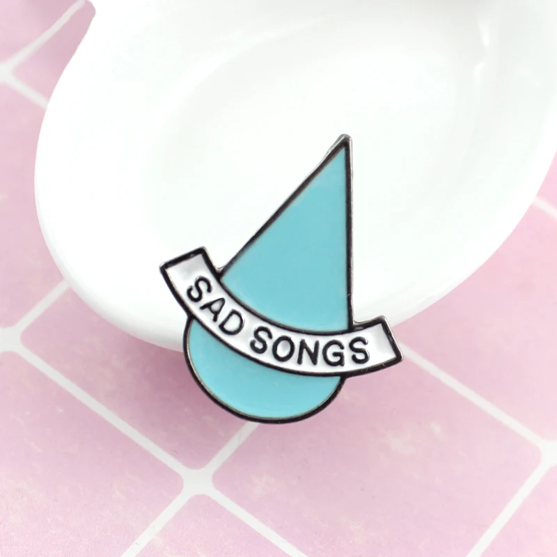 La spilla a forma di goccia blu &quotSAD SNOGS&quot rappresenta uno stato dɺnimo triste tristezza non convenzionale adatta agli amanti |