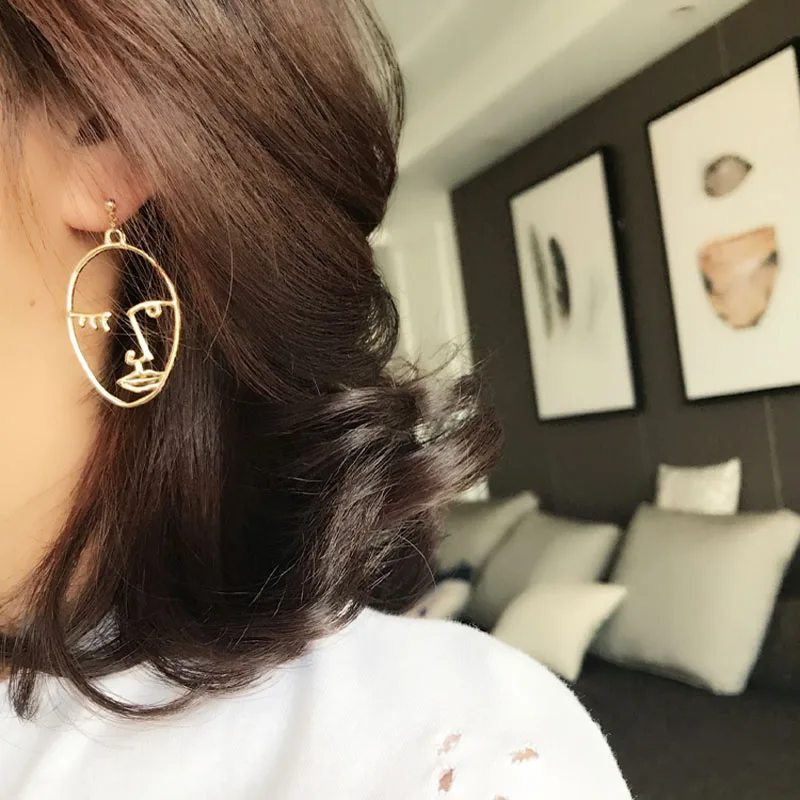 Женские серьги подвески золотистого цвета эффектные в форме лица или руки