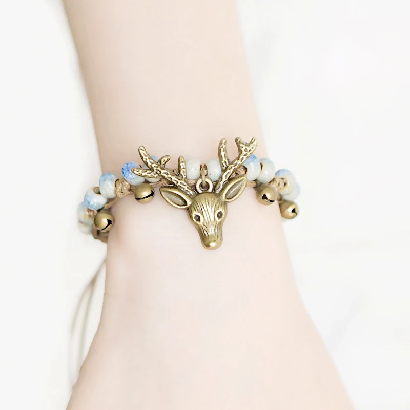 Женский браслет с шармами в виде головы оленя на запястье керамическими бусинами