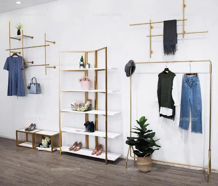 Clothing store display stand. Wall-hung in The Wall. Women's clothing store simple wrought iron gold. Side hangers.
