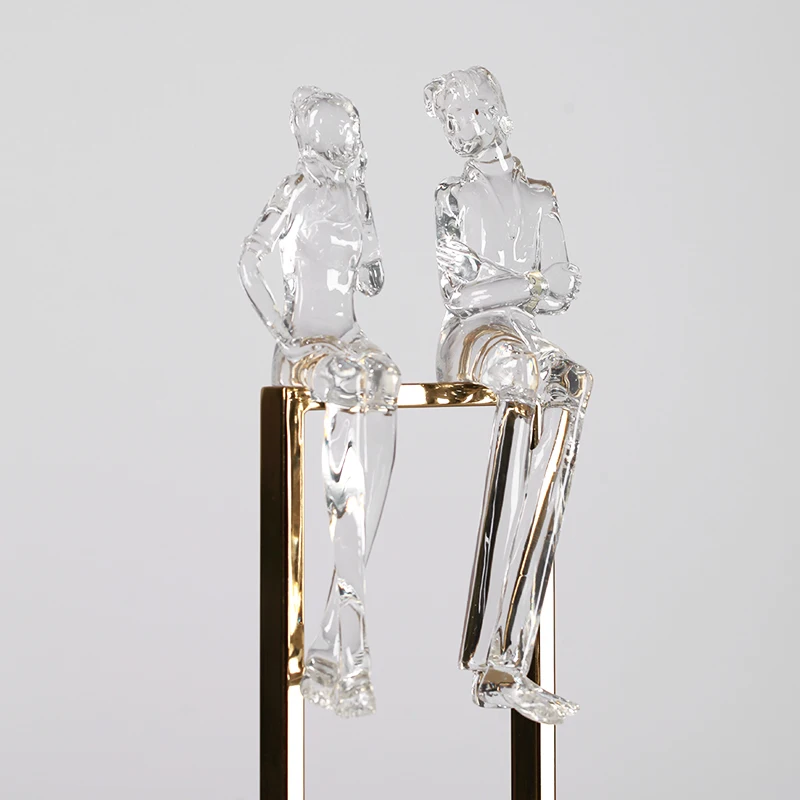 Творческая пара прозрачных абстрактных фигурок из смолы сидя на металлической