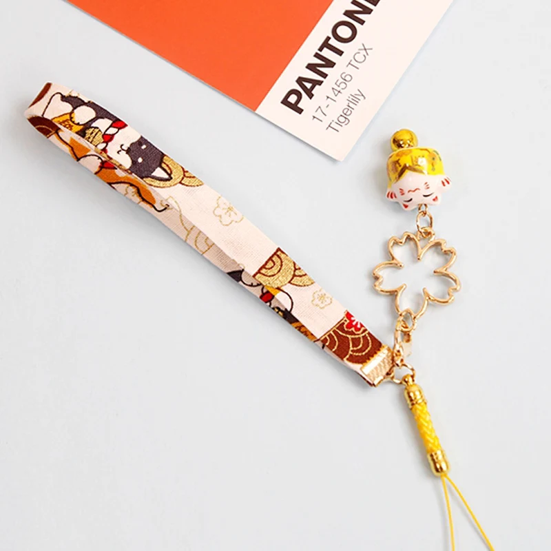 Японский брелок «Счастливый кот» цвета конфетки с колокольчиком и подвеской в виде вишневого цветка на верёвке для флешки или рюкзака. Аксессуары для ювелирных изделий.