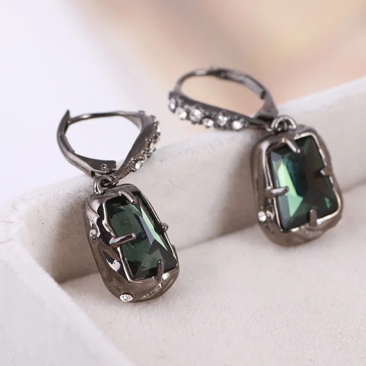 

Fashion earrings in black metal inlaid with green gemstones