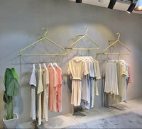 gold wall hanging clothes rack on display shelf of clothing store