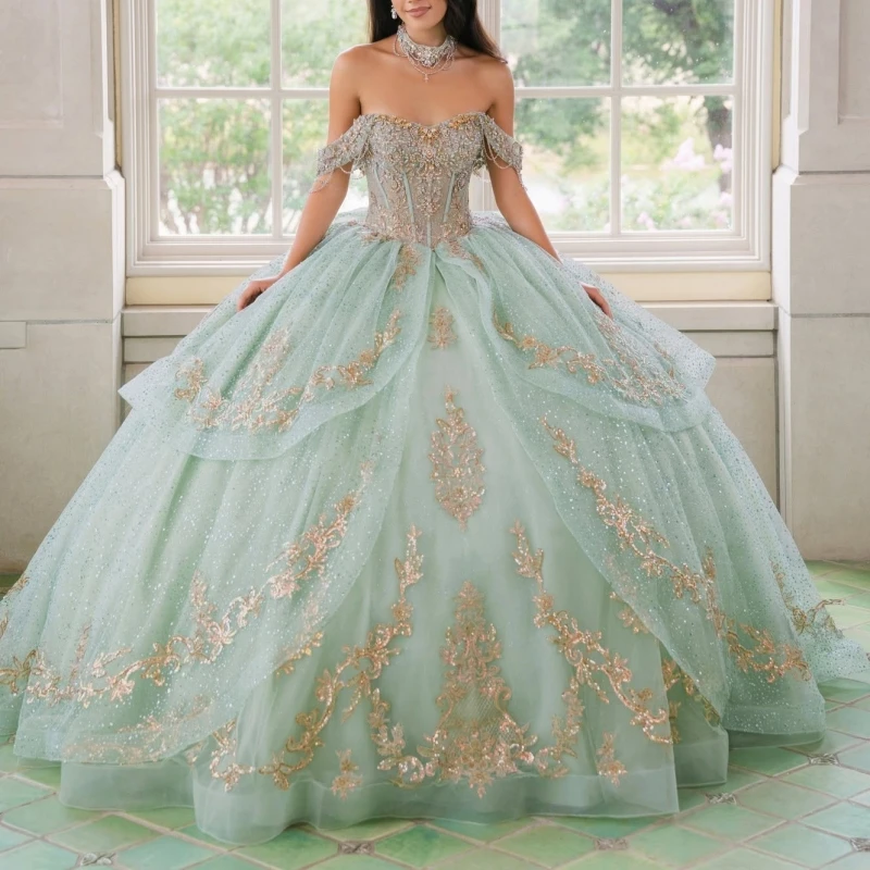 Фото Светло-зеленое блестящее бальное платье для Quinceanera с золотыми аппликациями, кружевом, бисером, кристаллами, бантом, тюлем, корсетом и открытыми плечами, для Sweet 16 №1