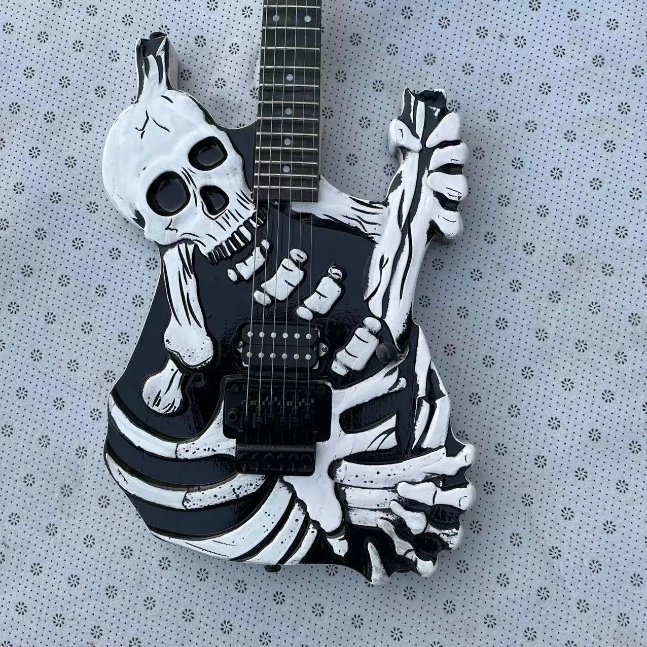 

Головка черепа-это сплит-электрогитара в старинном стиле с черно-белым корпусом, открытым картриджем, двойной поворотной струнной пластиной, розой