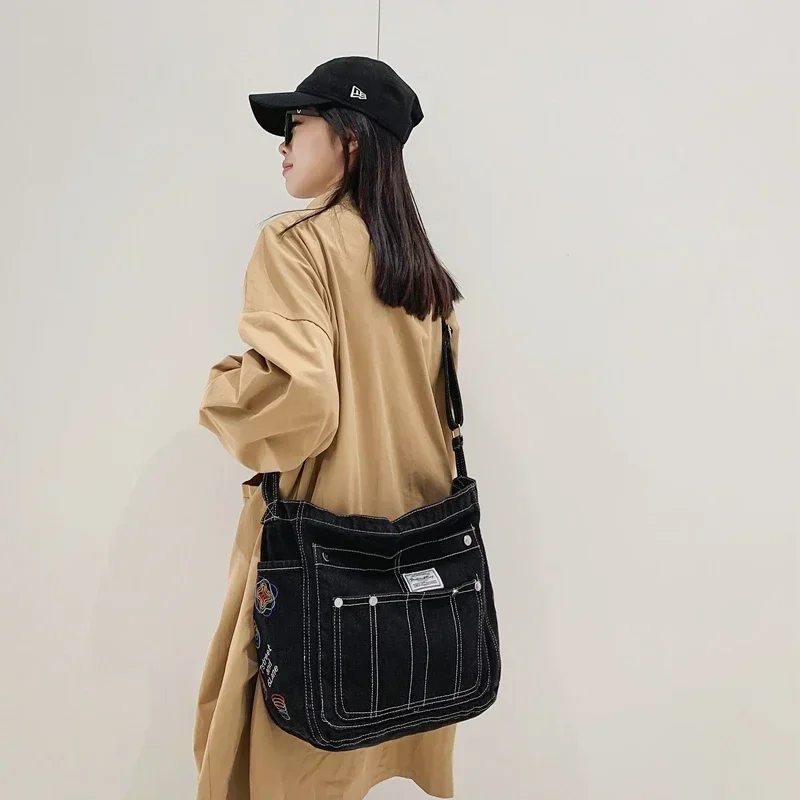 Потертая джинсовая сумка-книжка на плечо с синей вышивкой несколькими карманами