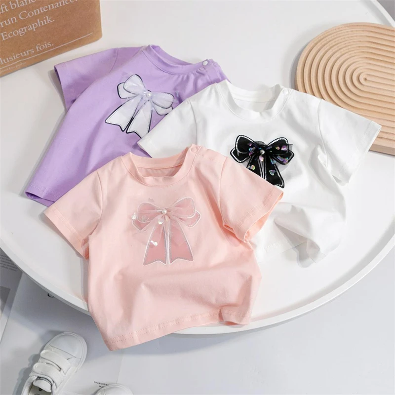 

Хлопковые футболки для девочек, футболки с простым мультяшным принтом и бантом, детские летние топы, одежда с коротким рукавом, белая, розовая, фиолетовая, модная одежда