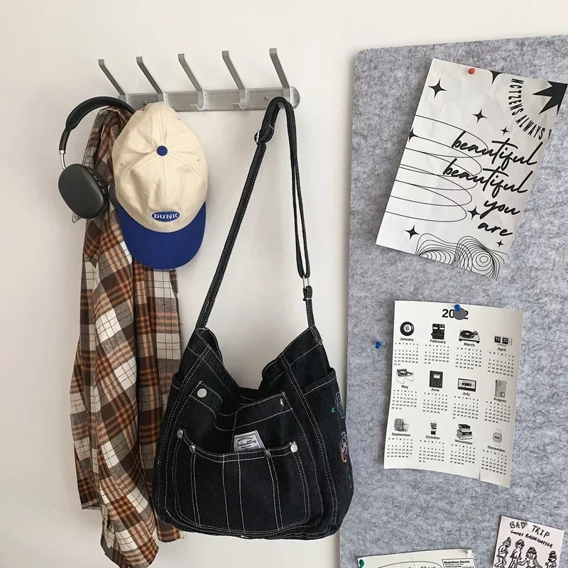 Потертая джинсовая сумка-книжка на плечо с синей вышивкой несколькими карманами