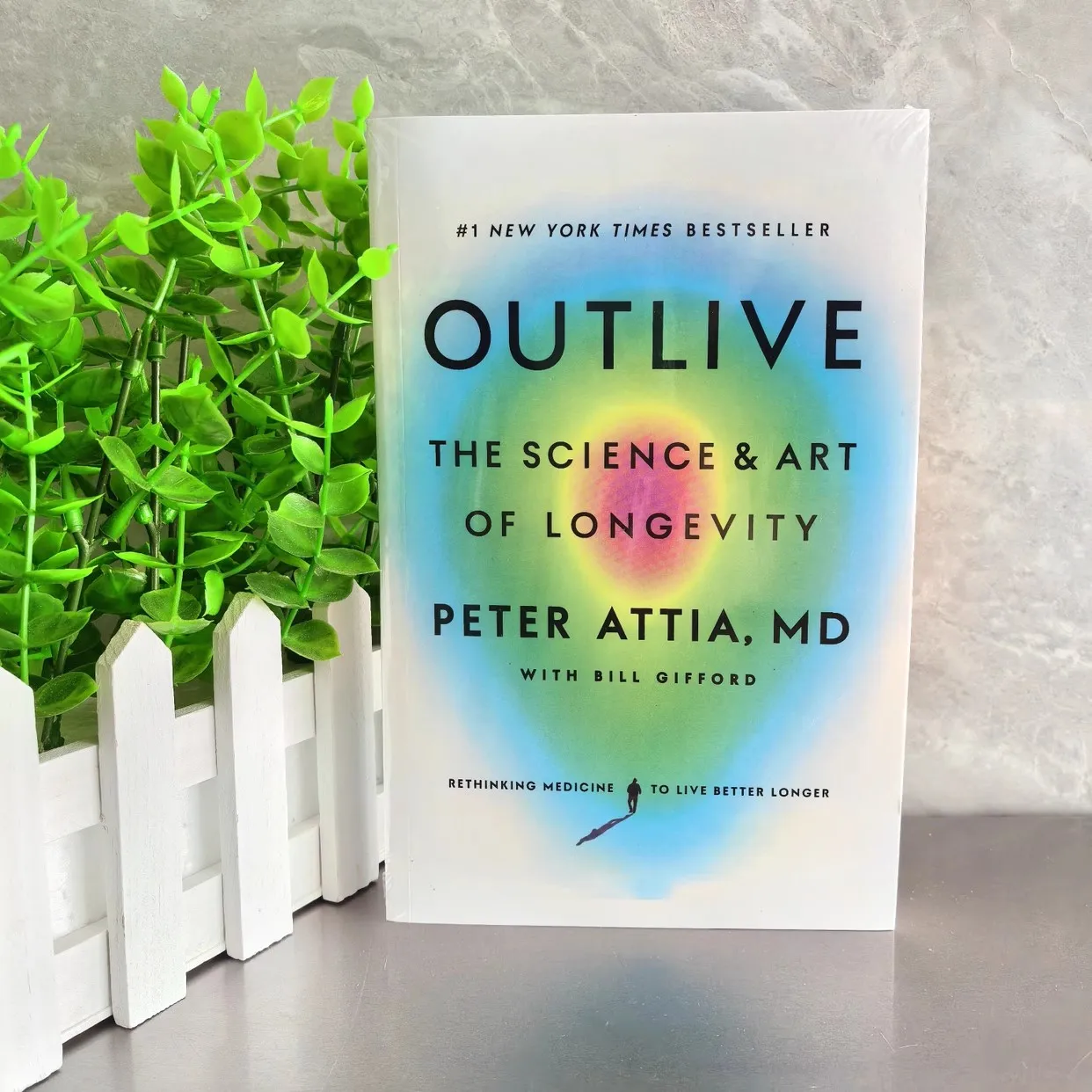 Книга в мягкой обложке с надписью Outlive The Science and Art of долговечность Петера аттиа на