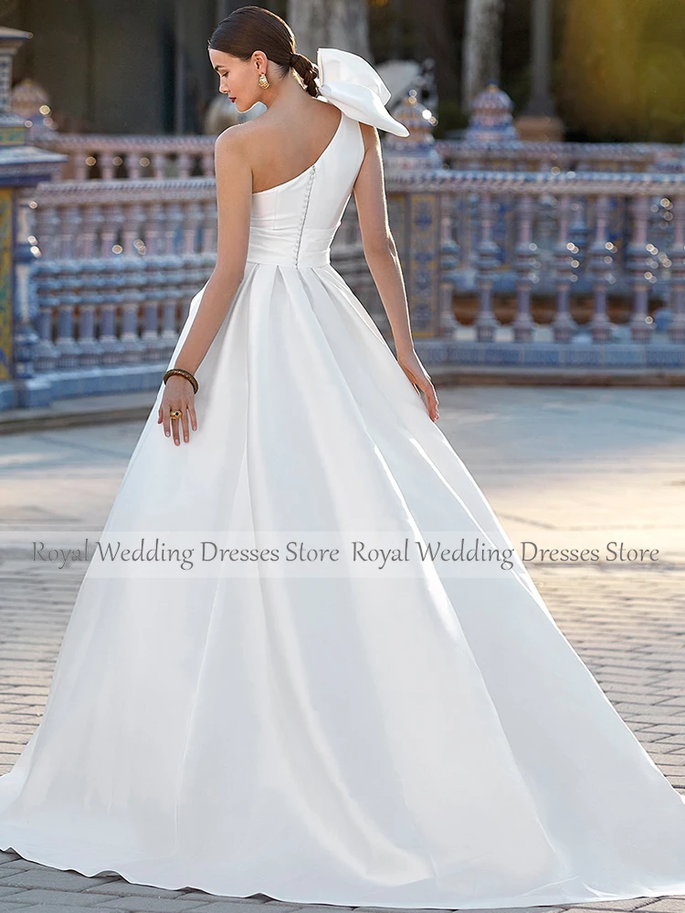 Атласное свадебное платье белого цвета на одно плечо с перьями и большим бантом