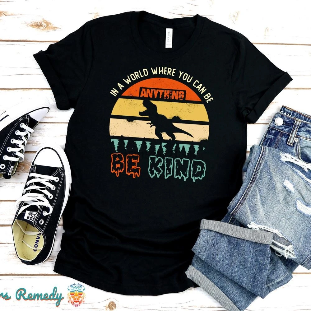 

TX In a World Where You Can Be Anything Be Kind T Shirt Retro Dinosaur Illustration Socially Conscious Nature Environment Vegan
