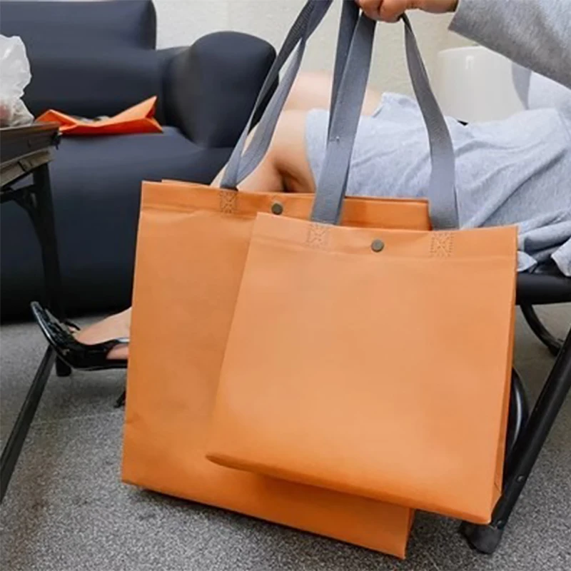 Нетканое изделие с логотипом на заказ кнопкой и ручкой для покупок одежда