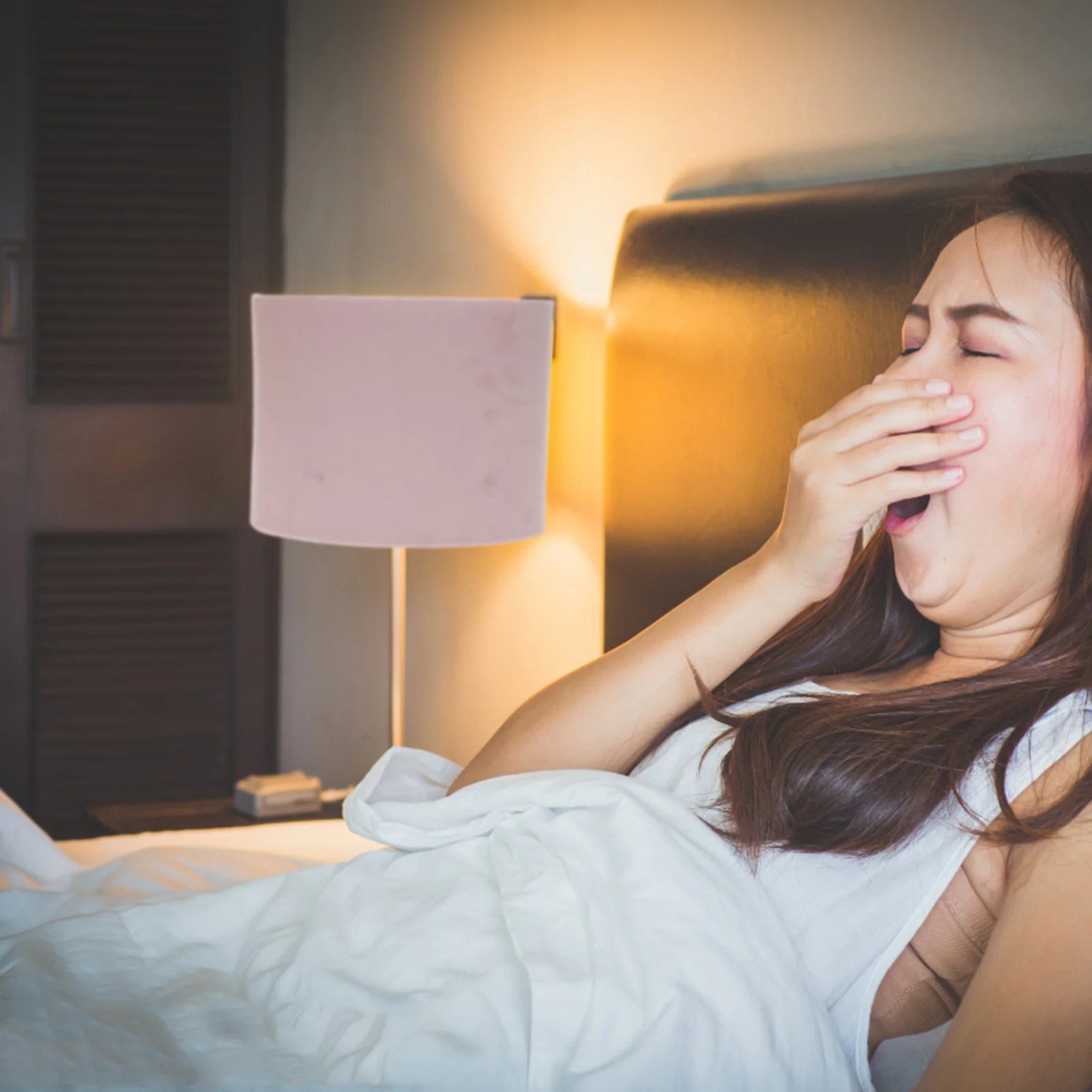 Девушка зевает. Лампа имитирующая солнечный свет для пробуждения. Синий свет и сон. Приготовление освещения ко сну в отеле. Спать со включенным светом.